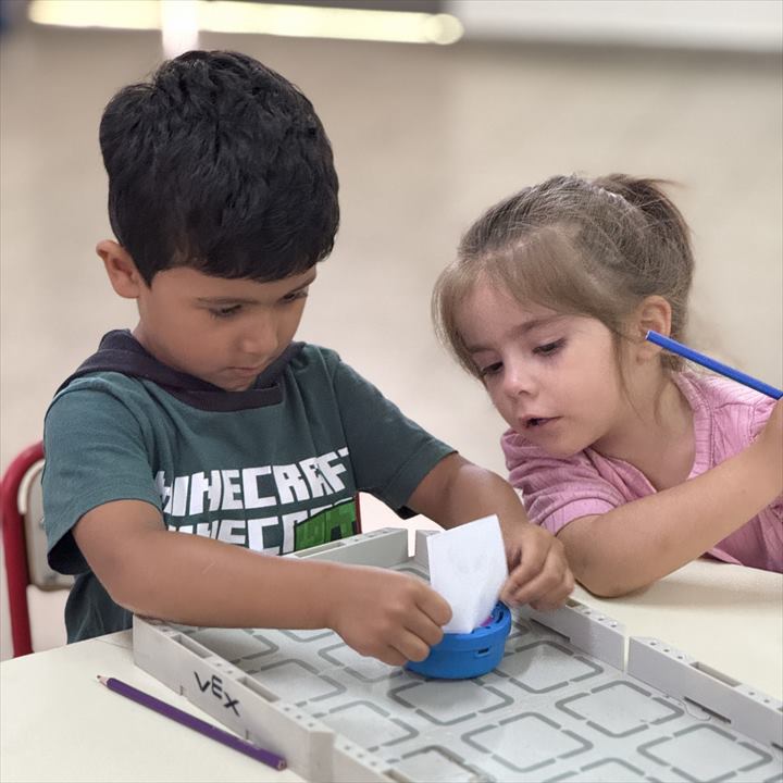 Dos chicos trabajan con una bandeja de piezas de robótica