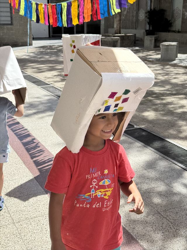 Un chico sonríe con una caja de cartón que decoró puesta en la cabeza