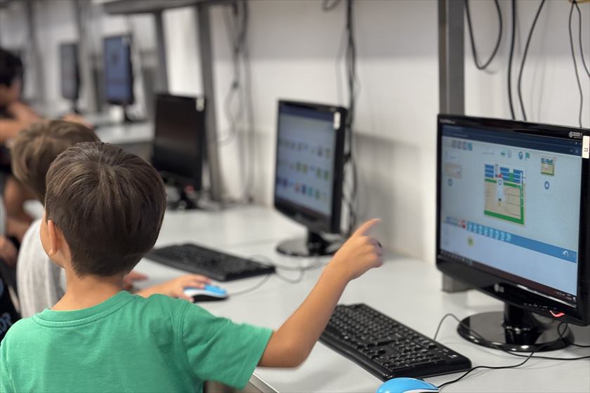 Chicos en la sala de computación: uno señala el proyecto en la pantalla