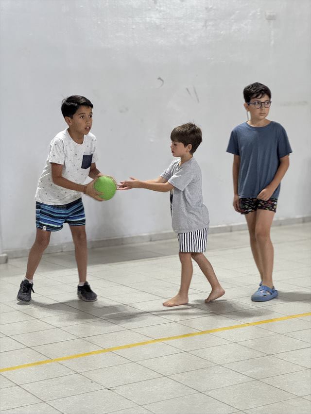 Tres chicos se pasan una pelota en el gimnasio